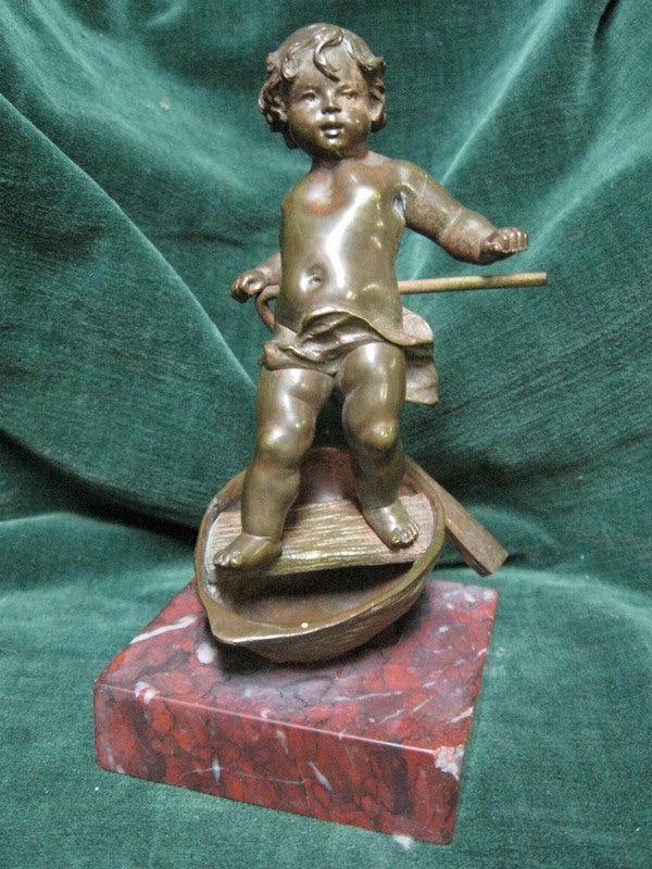 Bronze figure of a cherub sailing in a half walnut on a square marble base early 1900s