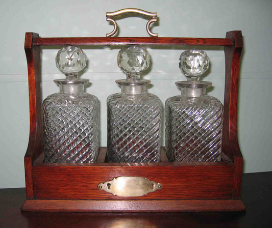 Oak cased 3 bottle Tantalus with plated mounts and original key